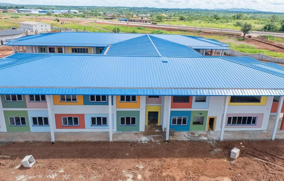 Le campus de la Cité du Savoir vu de loin : toiture bleue, bâtiments à façades colorées et horizon de Haute-Guinée