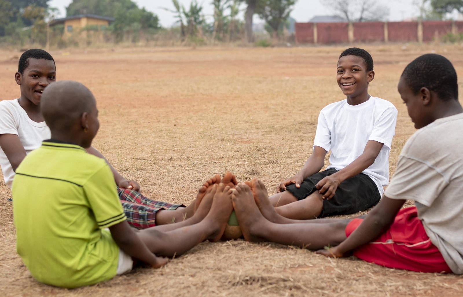 Des enfants assis en cercle sur la terre, pieds joints